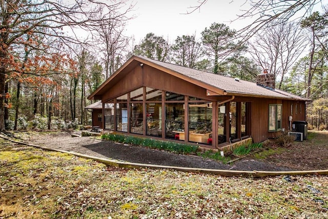 rear view of property with central AC unit and a sunroom