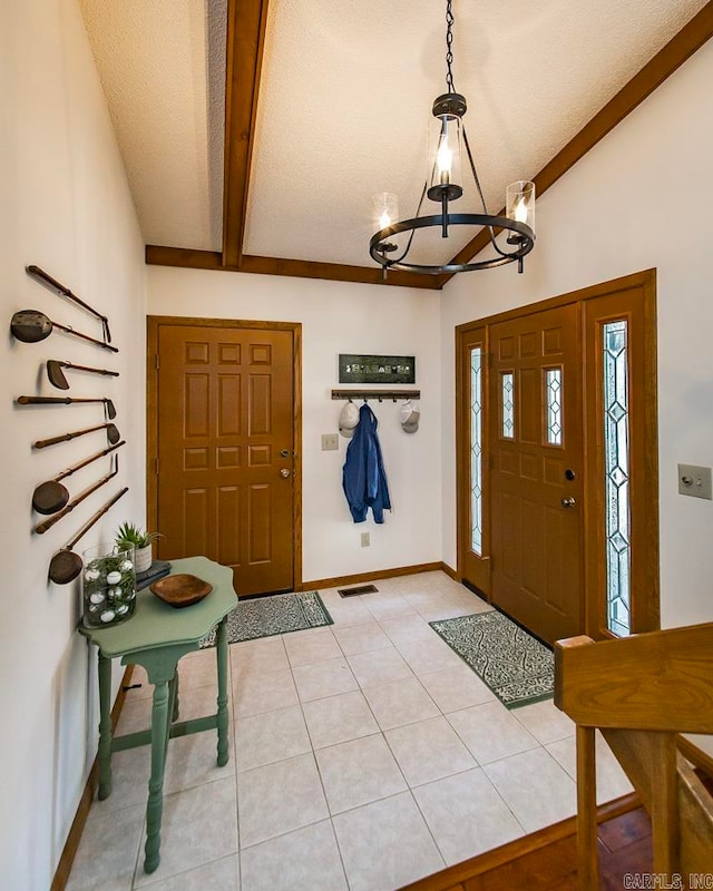 tiled foyer with a chandelier, vaulted ceiling with beams, and a textured ceiling