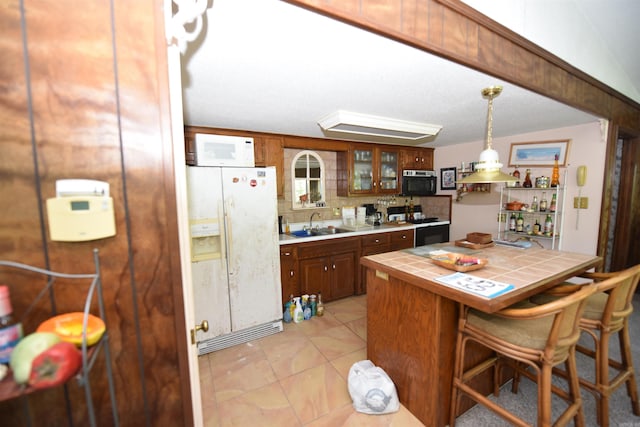 kitchen featuring pendant lighting, tasteful backsplash, tile counters, black appliances, and a breakfast bar area