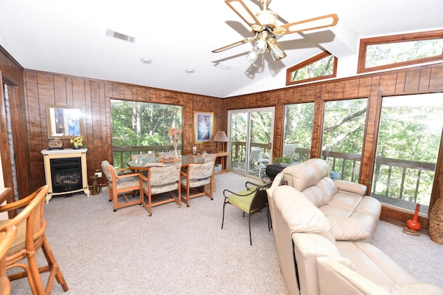 carpeted living room featuring lofted ceiling, wood walls, and ceiling fan