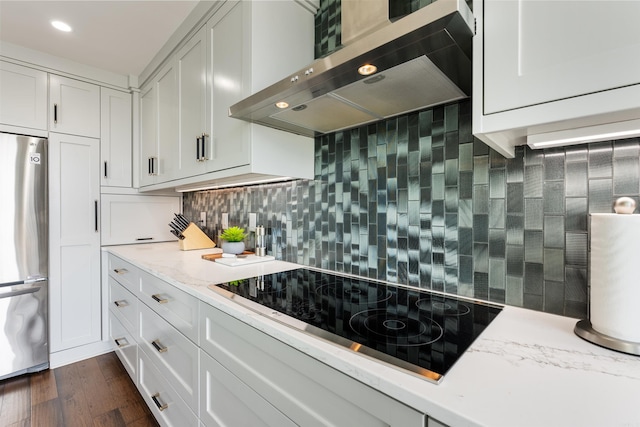 kitchen with dark hardwood / wood-style floors, stainless steel fridge, backsplash, black electric cooktop, and wall chimney range hood