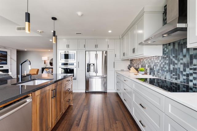 kitchen with built in appliances, wall chimney exhaust hood, dark wood-type flooring, sink, and white cabinetry