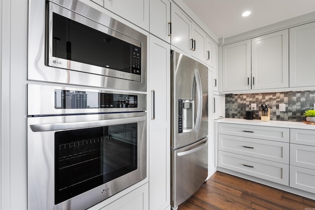 kitchen featuring white cabinets, stainless steel appliances, decorative backsplash, and dark hardwood / wood-style floors