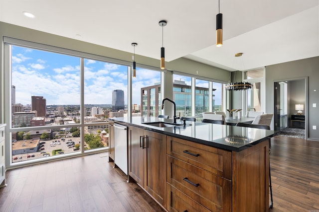 kitchen featuring decorative light fixtures, sink, an island with sink, dark wood-type flooring, and a breakfast bar