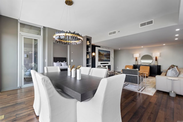 dining space featuring a fireplace, dark hardwood / wood-style floors, and an inviting chandelier