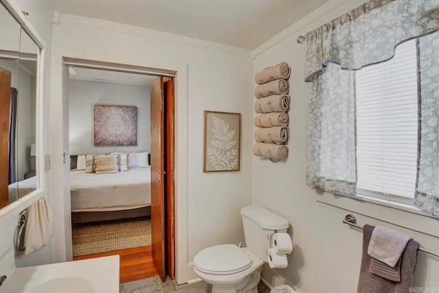 bathroom featuring ornamental molding, toilet, and wood-type flooring