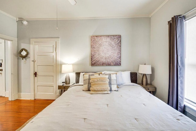 bedroom with multiple windows, wood-type flooring, and ornamental molding