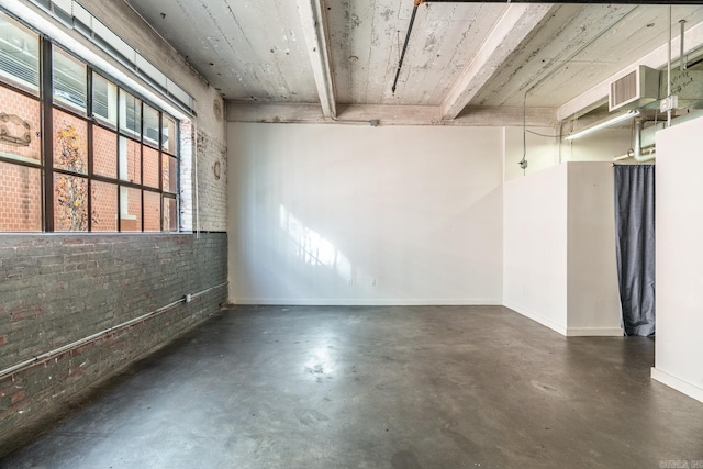 unfurnished room with brick wall and beam ceiling