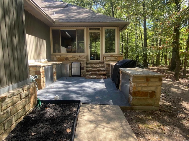 view of patio / terrace featuring exterior kitchen, a sunroom, and a grill