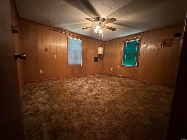 spare room with a textured ceiling, ceiling fan, carpet floors, and wooden walls