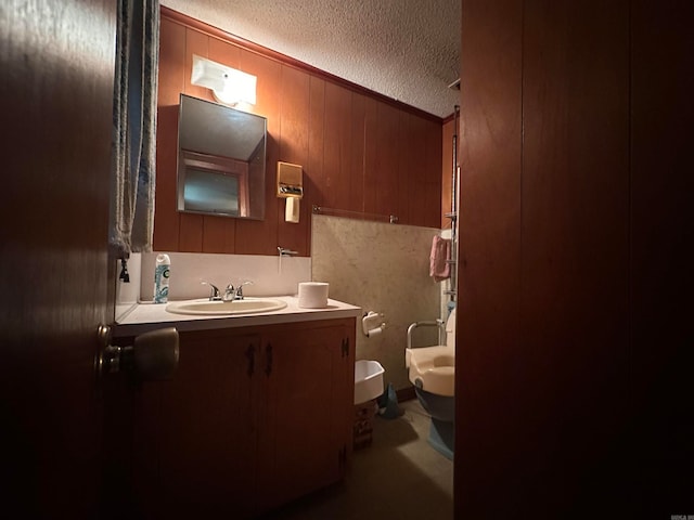 bathroom featuring toilet, a textured ceiling, and vanity