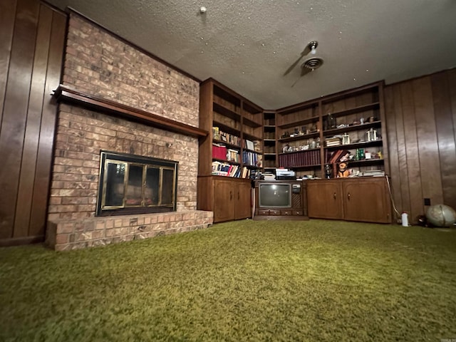 interior space featuring a textured ceiling, carpet flooring, wood walls, and a fireplace