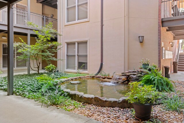 view of side of property featuring a balcony and a small pond