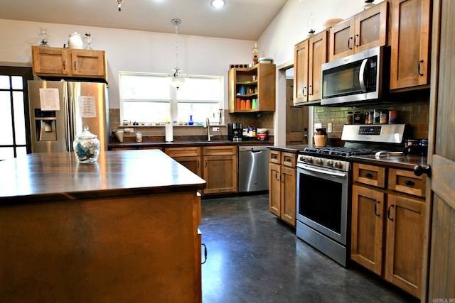 kitchen with decorative light fixtures, stainless steel appliances, sink, a kitchen island, and decorative backsplash