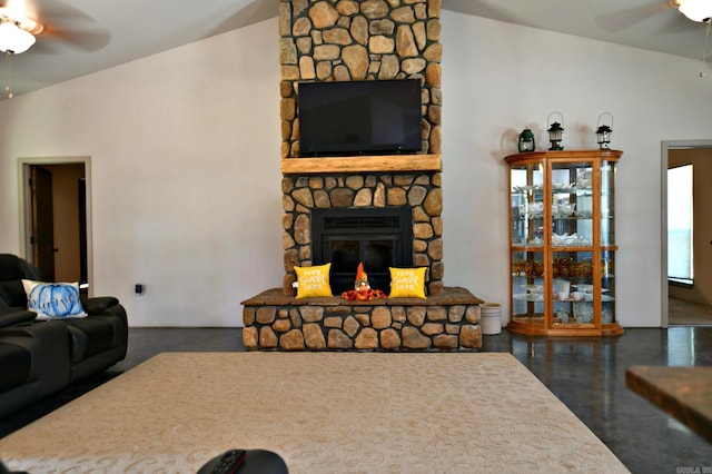 living room with a stone fireplace, ceiling fan, and vaulted ceiling