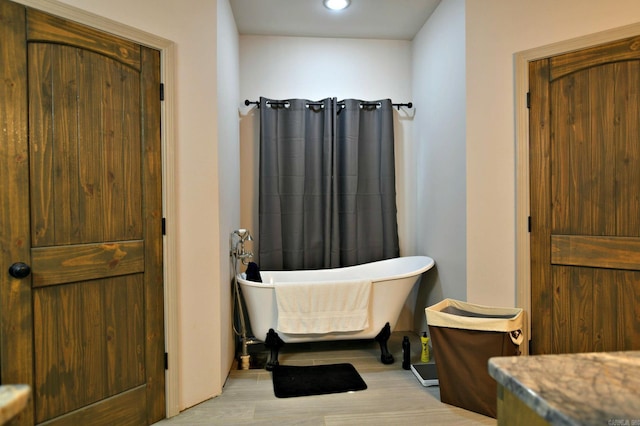 bathroom with a tub to relax in and wood-type flooring