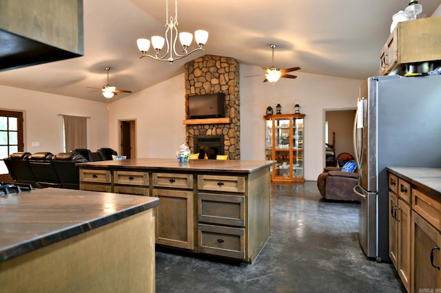 kitchen featuring stainless steel fridge, vaulted ceiling, ceiling fan with notable chandelier, and a fireplace