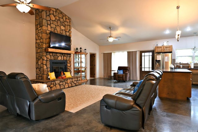 living room featuring lofted ceiling, a healthy amount of sunlight, ceiling fan, and a stone fireplace