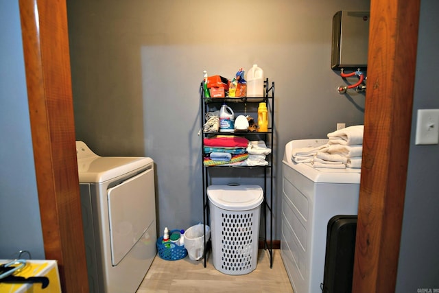 laundry room featuring light wood-type flooring, washing machine and clothes dryer, and water heater