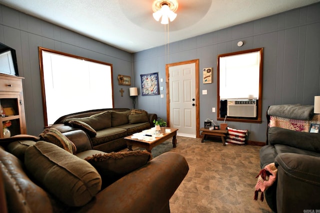 living room featuring a textured ceiling, cooling unit, and ceiling fan