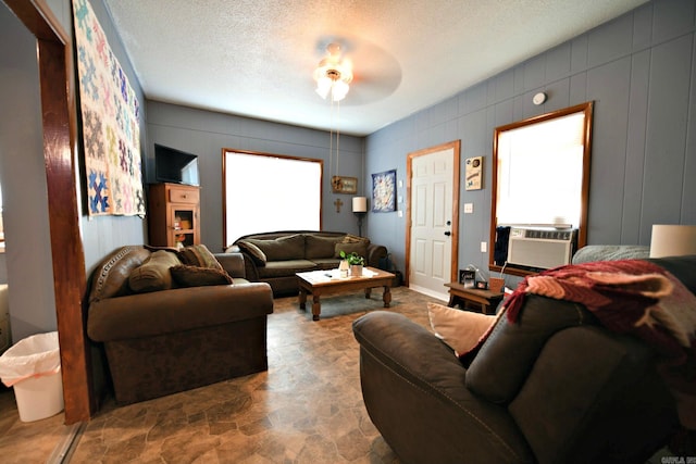 living room featuring cooling unit, ceiling fan, and a textured ceiling