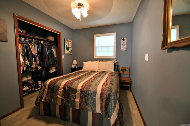 bedroom featuring a closet, ceiling fan, wood-type flooring, and a textured ceiling