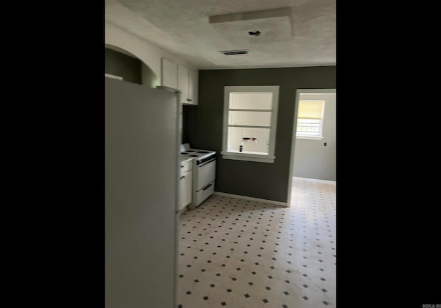 kitchen with a textured ceiling, white cabinets, and white appliances