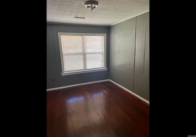 spare room featuring dark hardwood / wood-style floors and crown molding