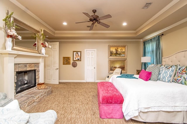 carpeted bedroom featuring ornamental molding, a tray ceiling, ceiling fan, and a stone fireplace