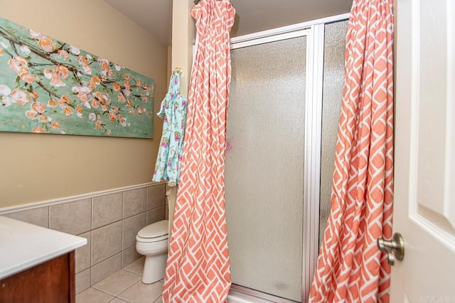 bathroom with vanity, walk in shower, tile walls, toilet, and tile patterned floors