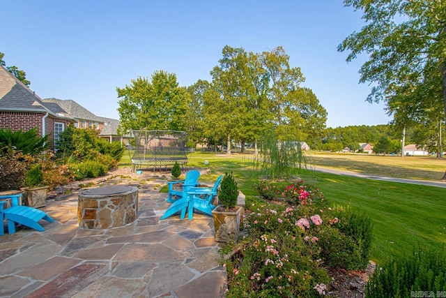 view of patio with a trampoline and an outdoor fire pit