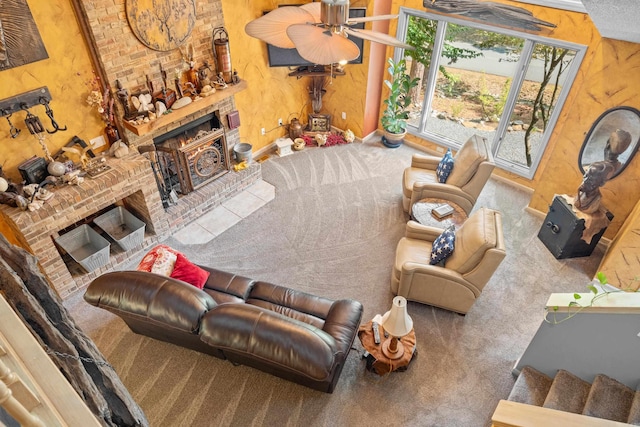 carpeted living room featuring a brick fireplace and ceiling fan