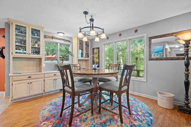 dining area featuring a textured ceiling, a chandelier, and light hardwood / wood-style floors