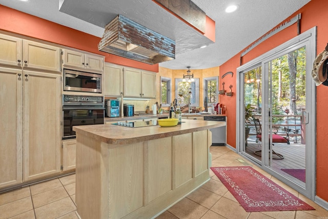 kitchen with appliances with stainless steel finishes, a textured ceiling, a kitchen island, and light tile patterned flooring