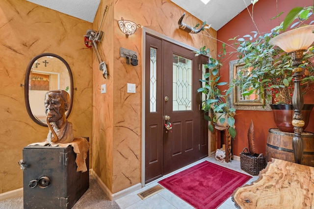 entryway with tile patterned floors, a textured ceiling, and vaulted ceiling