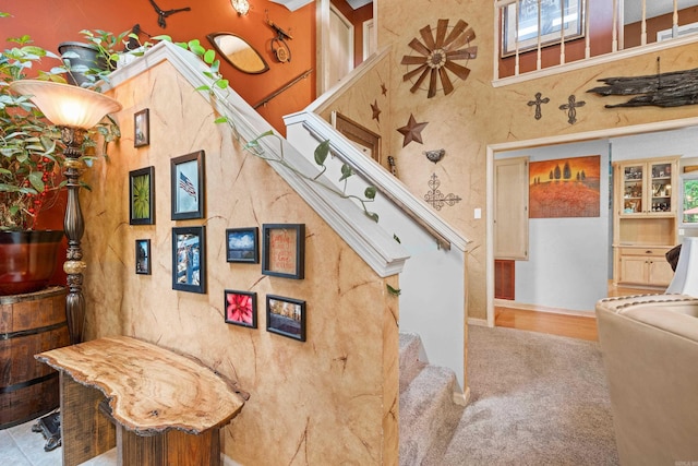 stairway featuring a high ceiling and carpet