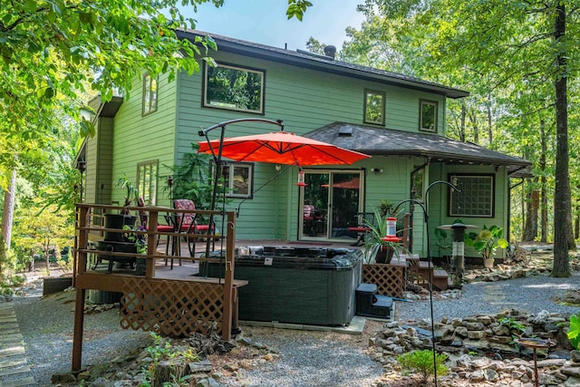 rear view of house featuring a hot tub and a deck