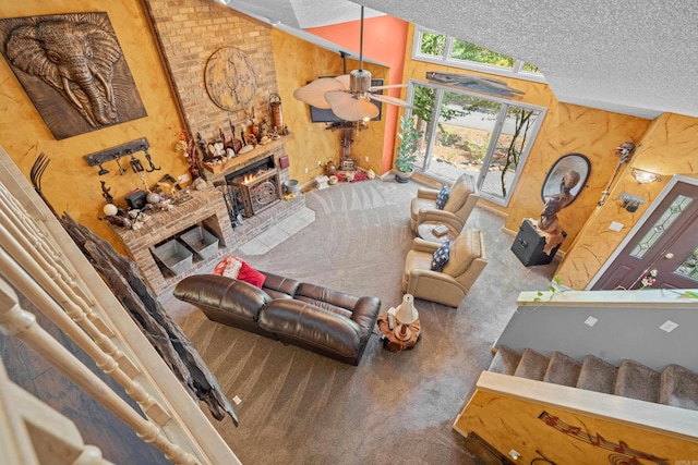 living room featuring a brick fireplace, high vaulted ceiling, carpet flooring, ceiling fan, and a textured ceiling