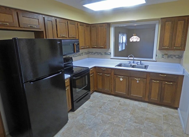 kitchen with hanging light fixtures, sink, decorative backsplash, and black appliances