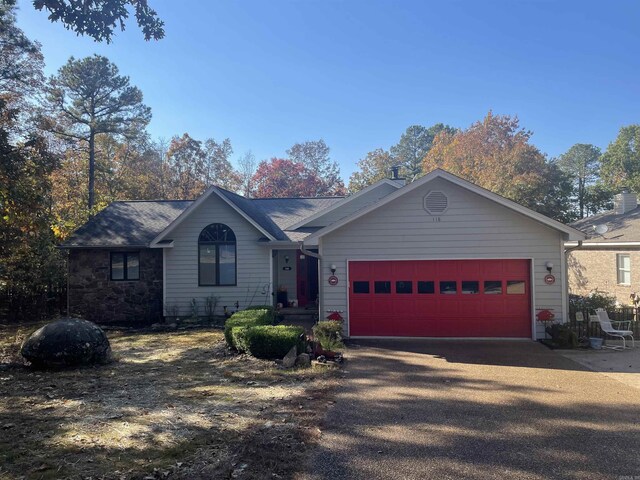 ranch-style house featuring a garage, stone siding, and driveway