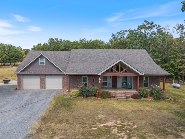 view of front of home with a garage, covered porch, and a front yard