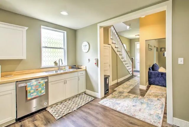 kitchen with dishwasher, light countertops, wood finished floors, white cabinets, and a sink