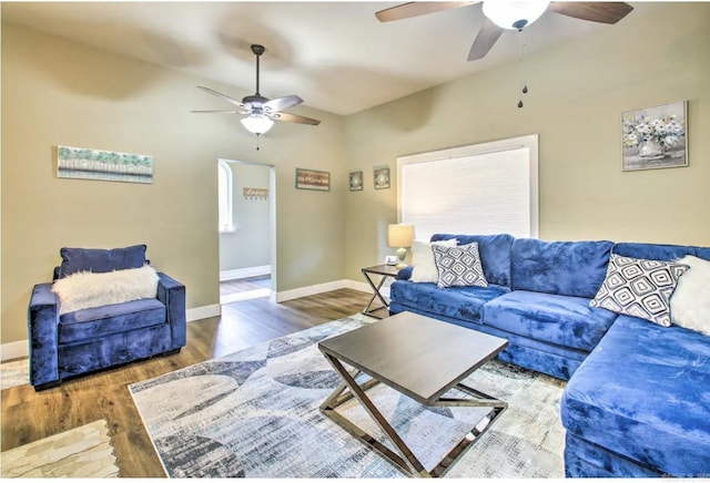 living area with baseboards, a ceiling fan, and wood finished floors