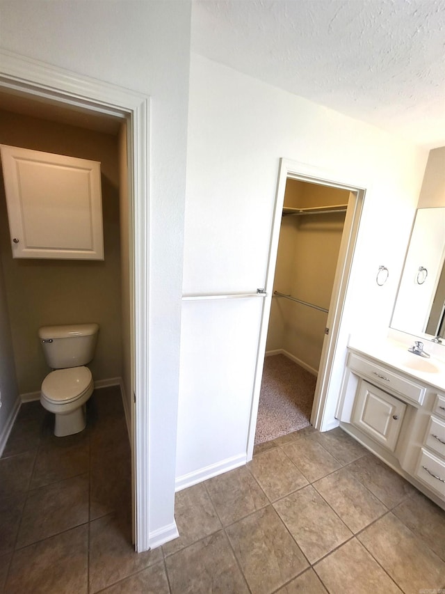 bathroom featuring tile patterned flooring, toilet, a textured ceiling, and vanity