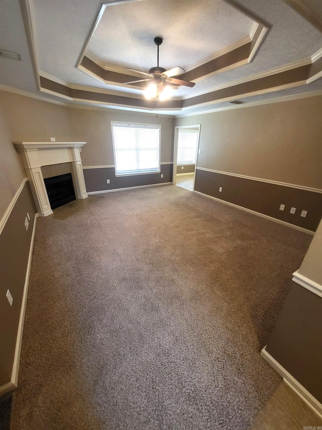 unfurnished living room featuring a tray ceiling, crown molding, ceiling fan, and carpet