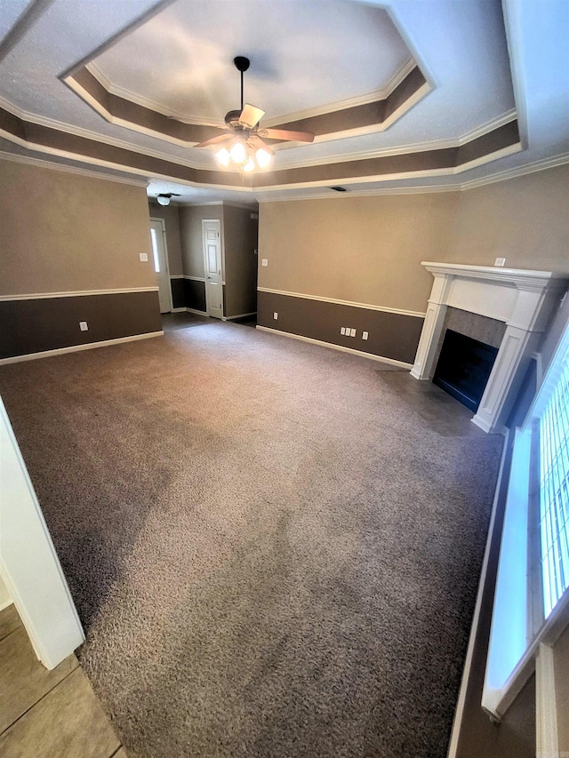 unfurnished living room with ceiling fan, a raised ceiling, and ornamental molding