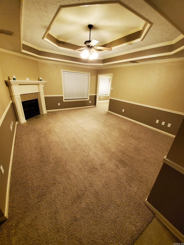 unfurnished living room featuring ornamental molding, a raised ceiling, ceiling fan, and carpet