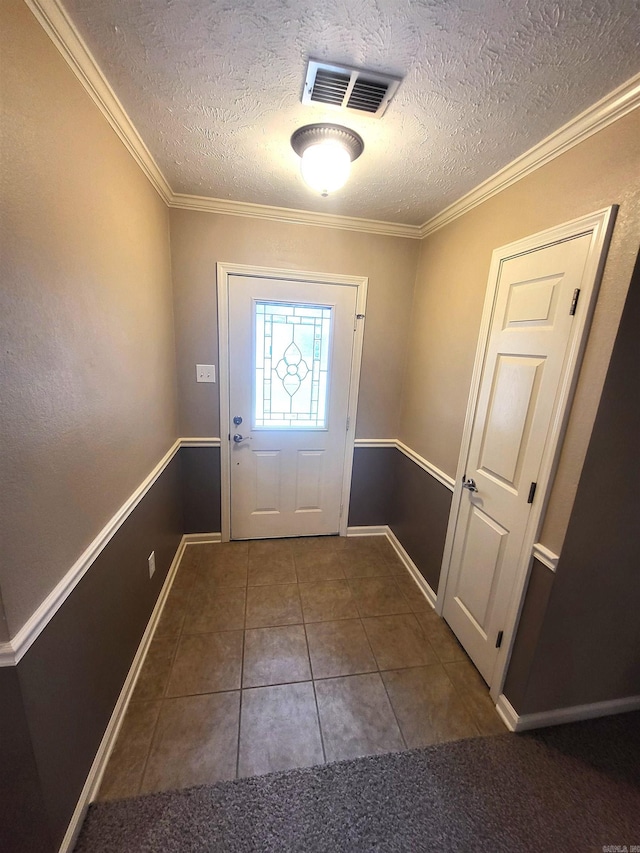 foyer with ornamental molding, dark tile patterned floors, and a textured ceiling