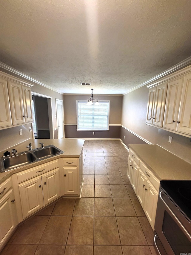 kitchen featuring a textured ceiling, crown molding, sink, tile patterned floors, and cream cabinetry