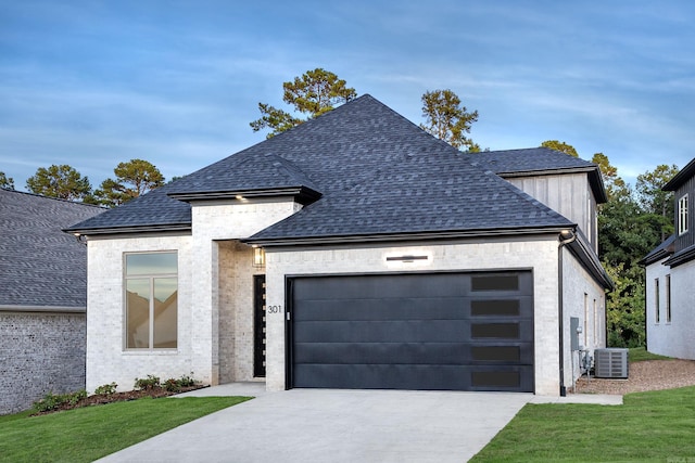 view of front of home featuring a garage, a front yard, and central AC unit